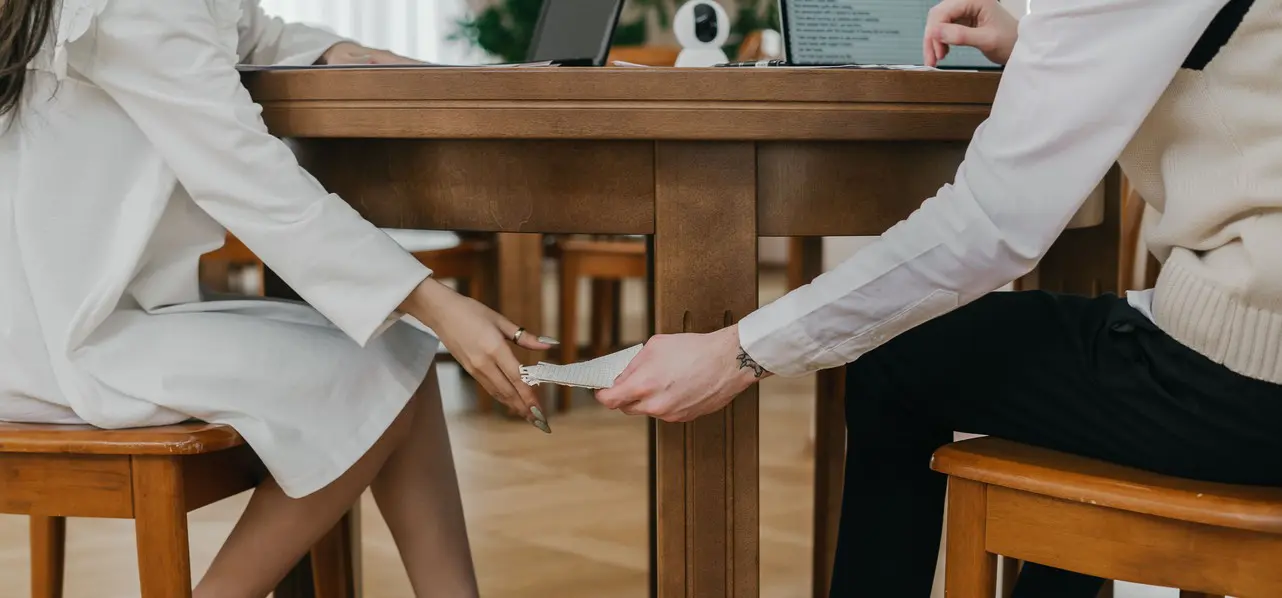 Two people passing a note under a table